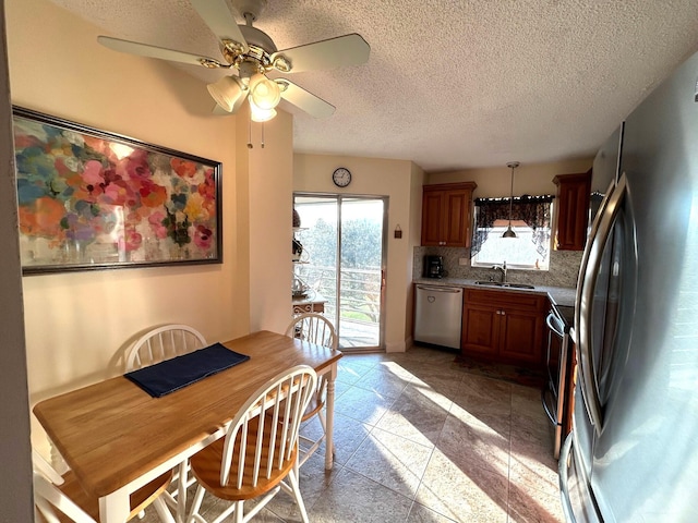 kitchen featuring sink, a textured ceiling, pendant lighting, stainless steel appliances, and decorative backsplash