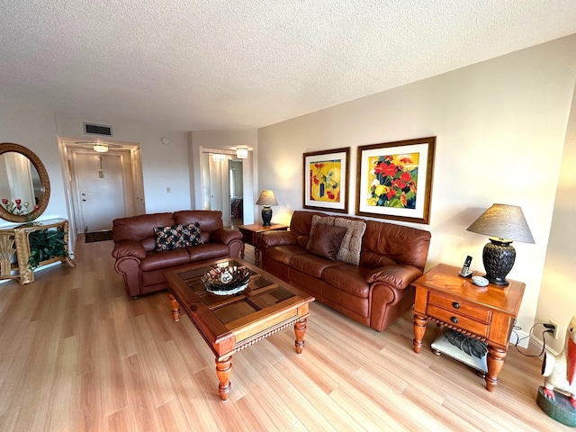 living room featuring a textured ceiling and light wood-type flooring