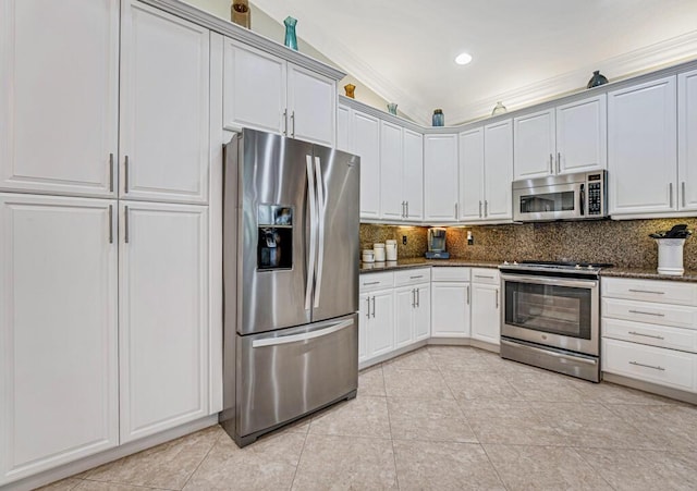 kitchen with appliances with stainless steel finishes, white cabinetry, decorative backsplash, dark stone counters, and light tile patterned floors