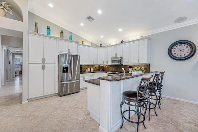 kitchen with white cabinetry, appliances with stainless steel finishes, and dark stone counters