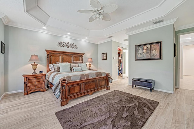 bedroom featuring ornamental molding, ceiling fan, light hardwood / wood-style floors, and a tray ceiling