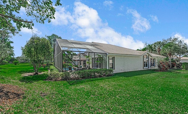 back of property featuring glass enclosure and a lawn