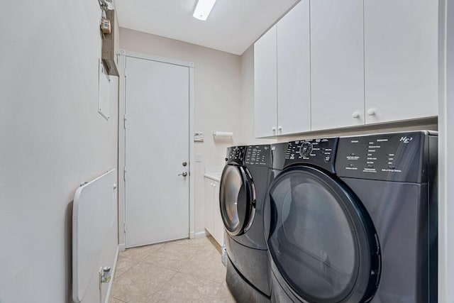 clothes washing area featuring cabinets, separate washer and dryer, and light tile patterned floors