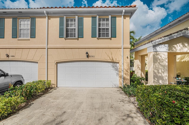 exterior space featuring a garage, driveway, and stucco siding