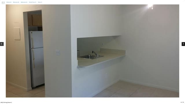 kitchen with sink, white fridge, and light tile patterned floors