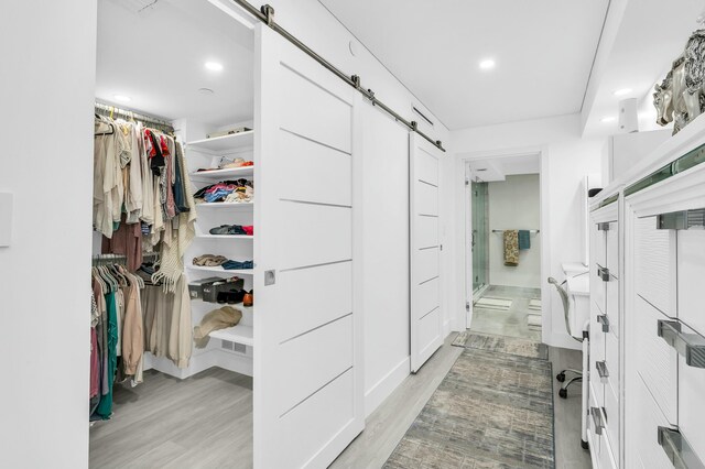 1155 Hillsboro Mile Unit 202, Hillsboro Beach, FL 33062 - spacious closet featuring a barn door and light hardwood / wood-style floors