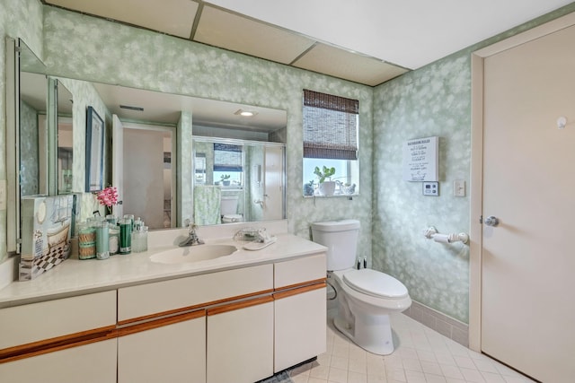 bathroom with tile patterned flooring, vanity, a shower with shower door, and toilet