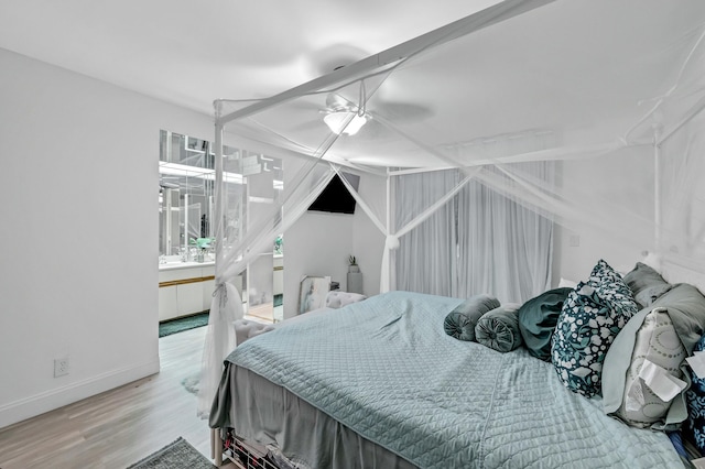 bedroom with ceiling fan, connected bathroom, and light hardwood / wood-style flooring