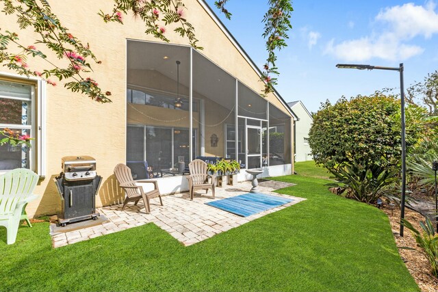 back of property featuring a yard, a sunroom, and a patio