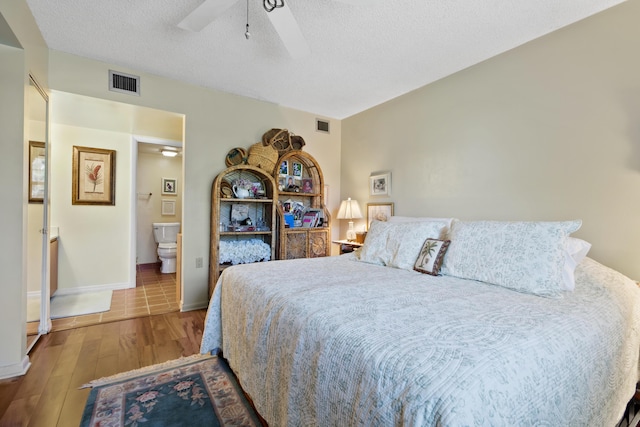 bedroom featuring connected bathroom, ceiling fan, light hardwood / wood-style floors, and a textured ceiling