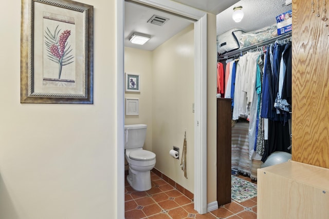 bathroom with tile patterned flooring, a textured ceiling, and toilet