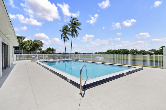 view of swimming pool featuring a patio and a water view