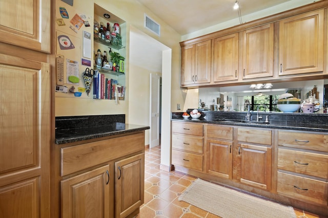 kitchen featuring light tile patterned flooring, dark stone counters, and sink