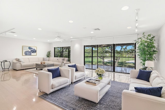 living room with track lighting, ceiling fan, and light wood-type flooring