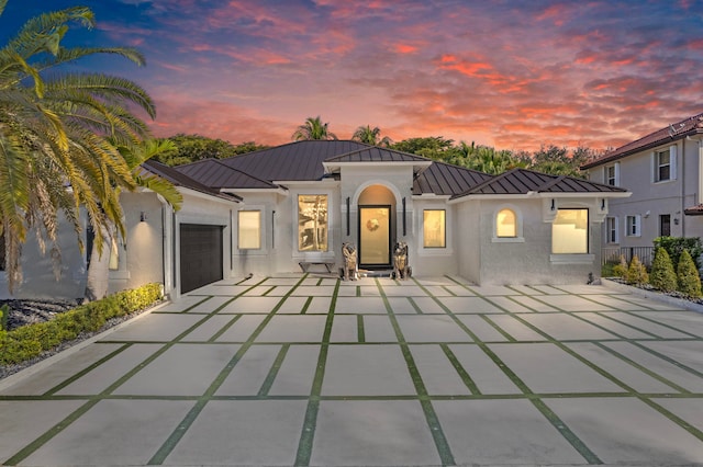 back house at dusk featuring a garage