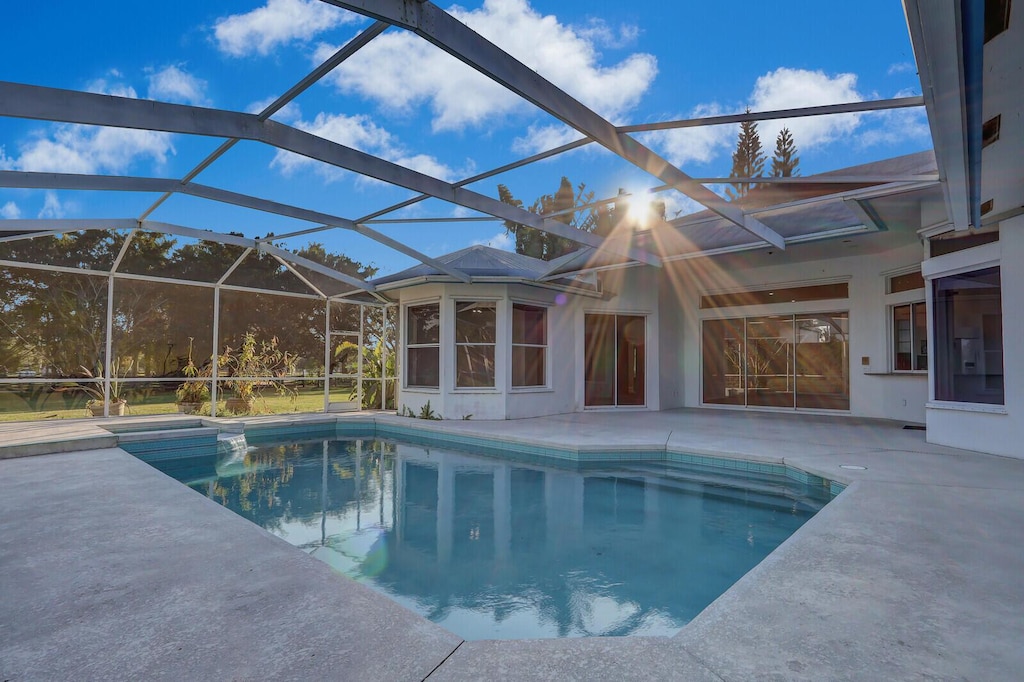 view of pool featuring a patio, a sunroom, and glass enclosure