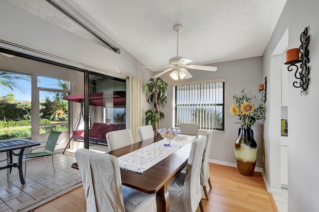 dining room with lofted ceiling, a healthy amount of sunlight, light hardwood / wood-style flooring, and a textured ceiling