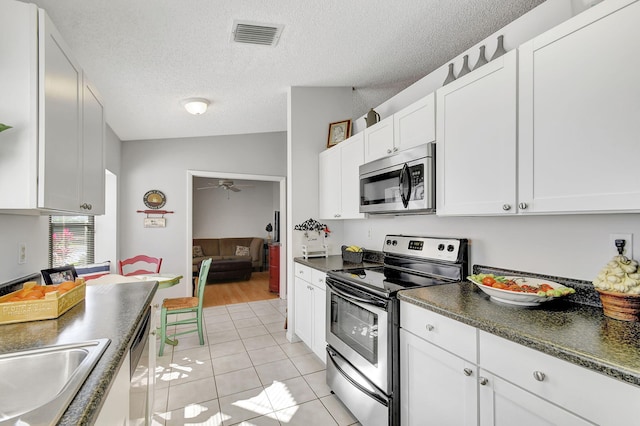 kitchen featuring white cabinetry, vaulted ceiling, stainless steel appliances, and light tile patterned flooring