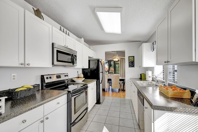 kitchen with sink, light tile patterned flooring, white cabinets, and appliances with stainless steel finishes