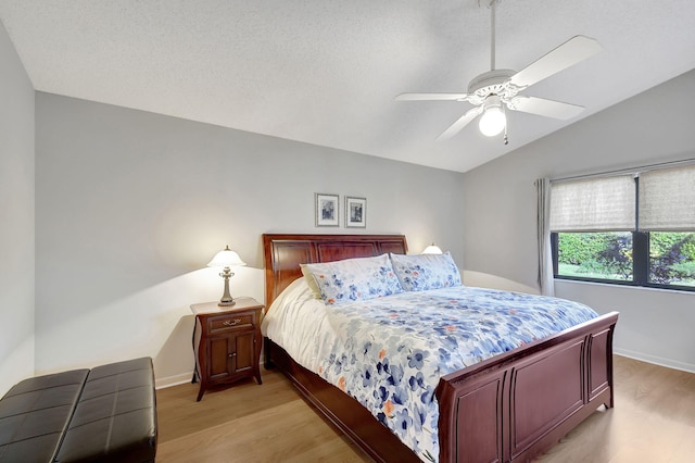 bedroom featuring ceiling fan, vaulted ceiling, light hardwood / wood-style flooring, and a textured ceiling