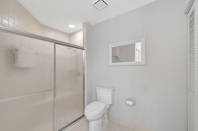 bathroom with tile patterned flooring, toilet, and a shower with shower door