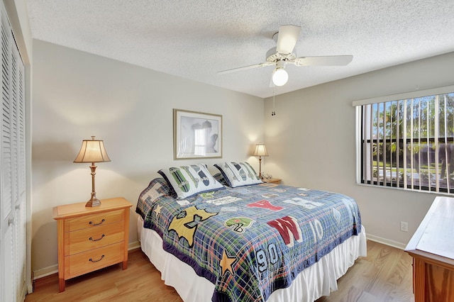 bedroom featuring ceiling fan, a closet, light hardwood / wood-style flooring, and a textured ceiling