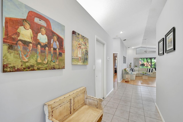 hall featuring vaulted ceiling and light tile patterned flooring