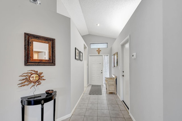 hall featuring light tile patterned flooring, lofted ceiling, and a textured ceiling