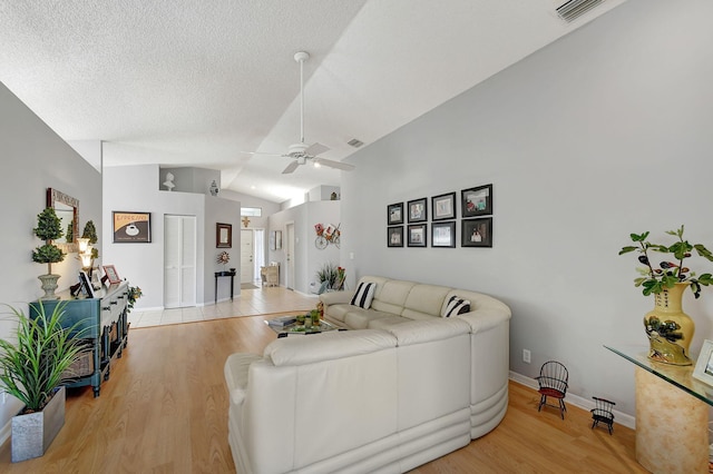 living room with a textured ceiling, vaulted ceiling, light hardwood / wood-style floors, and ceiling fan