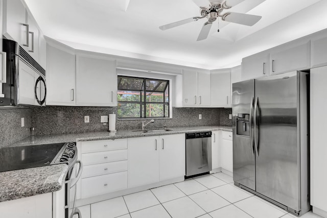 kitchen featuring sink, appliances with stainless steel finishes, white cabinetry, decorative backsplash, and dark stone counters