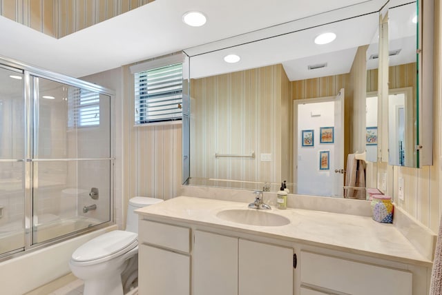 full bathroom with vanity, bath / shower combo with glass door, and toilet