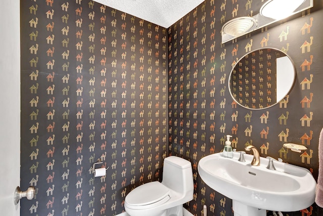 bathroom with toilet, sink, and a textured ceiling