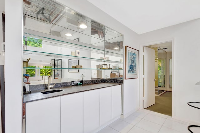 bar featuring white cabinetry, sink, and light tile patterned floors