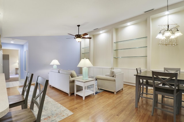 living room featuring ceiling fan with notable chandelier and light hardwood / wood-style floors