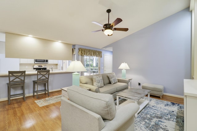 living room featuring vaulted ceiling, ceiling fan, and light wood-type flooring