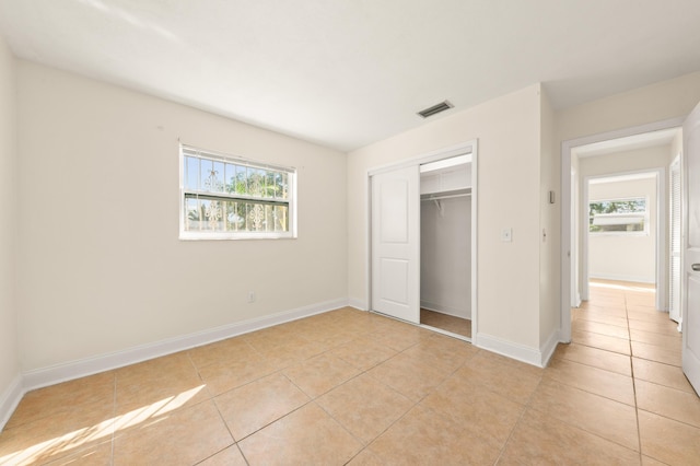 unfurnished bedroom with light tile patterned flooring, a closet, and multiple windows