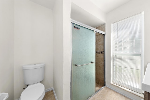 bathroom featuring toilet, a shower with shower door, and tile patterned flooring