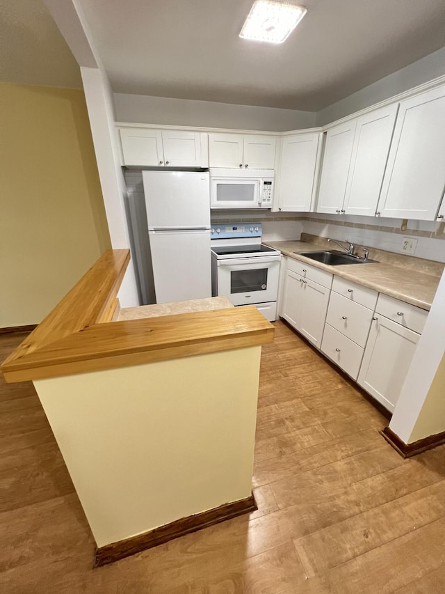 kitchen with sink, white cabinets, white appliances, light hardwood / wood-style floors, and backsplash