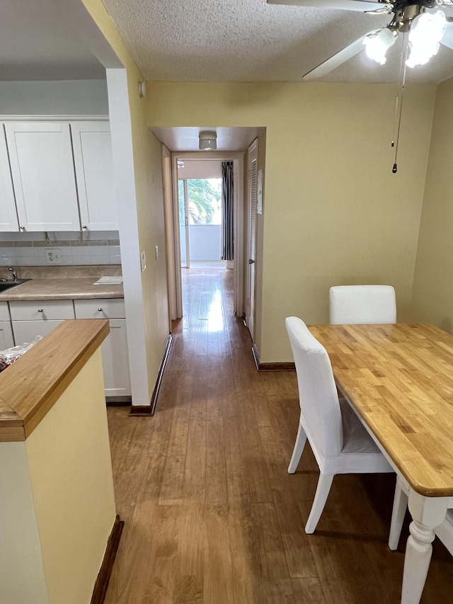 dining room featuring ceiling fan, light hardwood / wood-style flooring, sink, and a textured ceiling