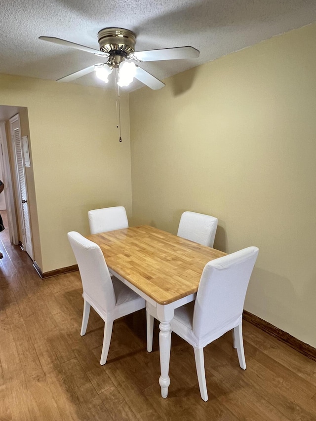 dining space with hardwood / wood-style flooring, ceiling fan, and a textured ceiling