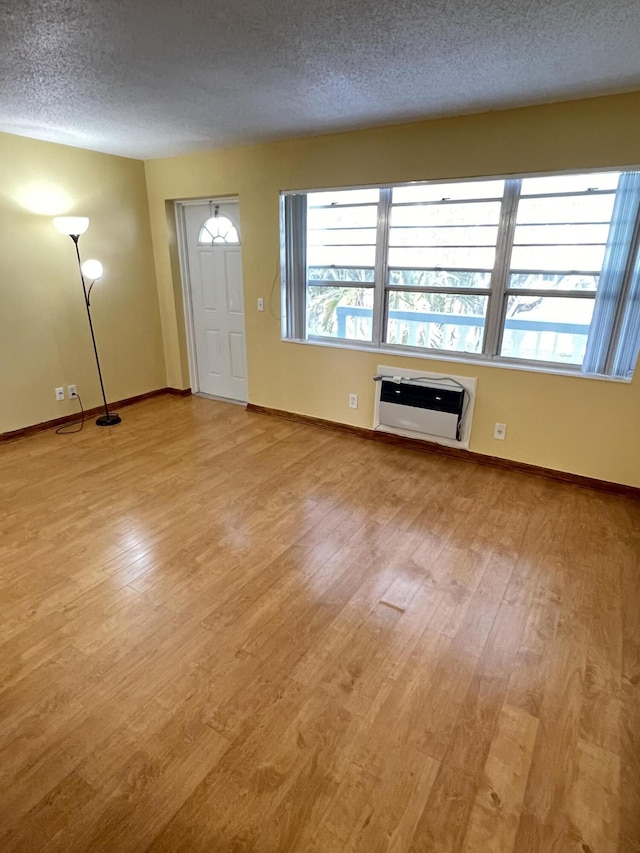 entryway with a textured ceiling, an AC wall unit, a healthy amount of sunlight, and light wood-type flooring