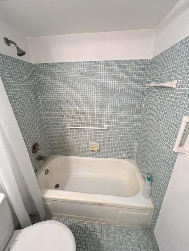 bathroom with toilet, tiled shower / bath combo, and tile patterned flooring