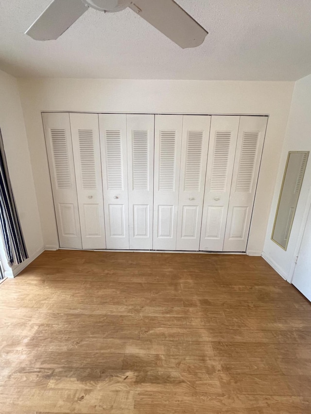 unfurnished bedroom featuring hardwood / wood-style flooring, ceiling fan, and a closet