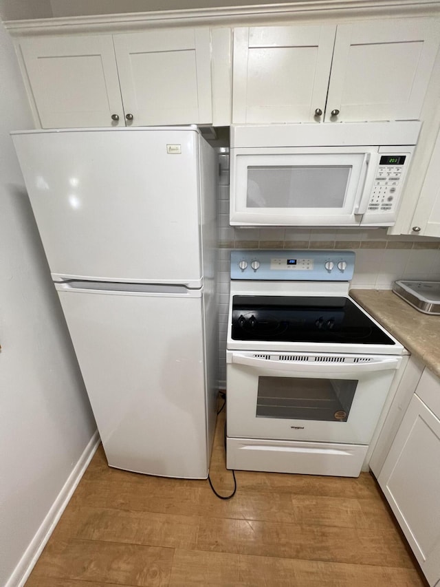 kitchen with white appliances, light hardwood / wood-style floors, decorative backsplash, and white cabinets