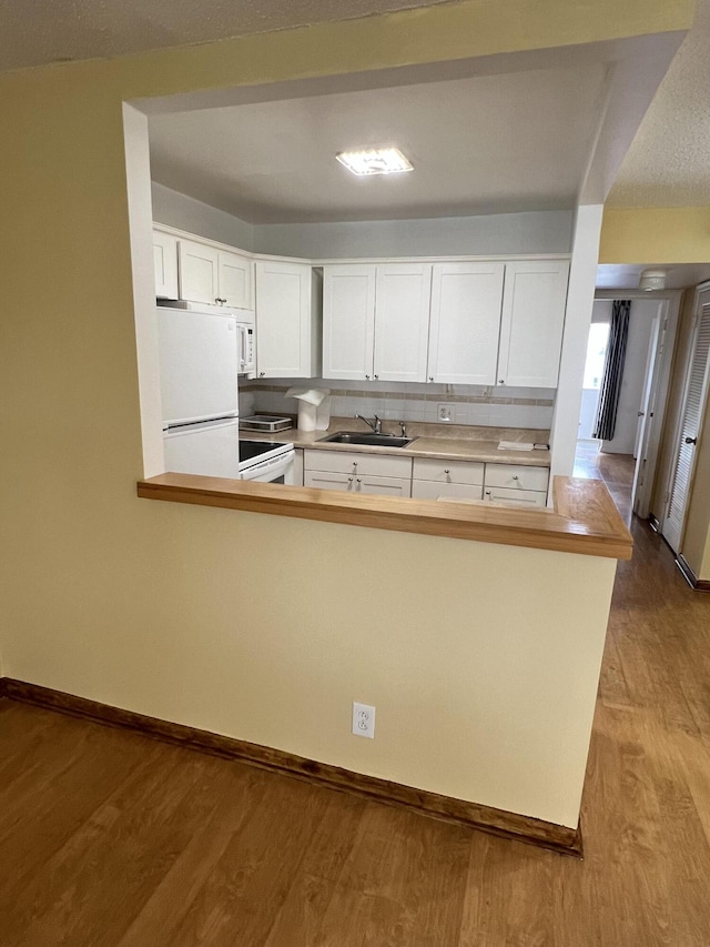 kitchen featuring sink, white cabinets, white appliances, kitchen peninsula, and light wood-type flooring