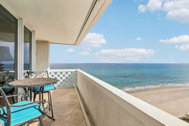 balcony featuring a view of the beach and a water view