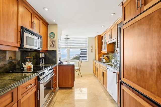 kitchen with tasteful backsplash, appliances with stainless steel finishes, sink, and dark stone countertops