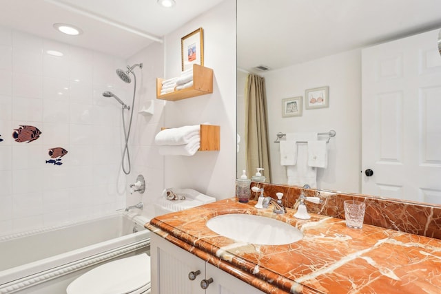 full bathroom featuring tiled shower / bath combo, vanity, and toilet