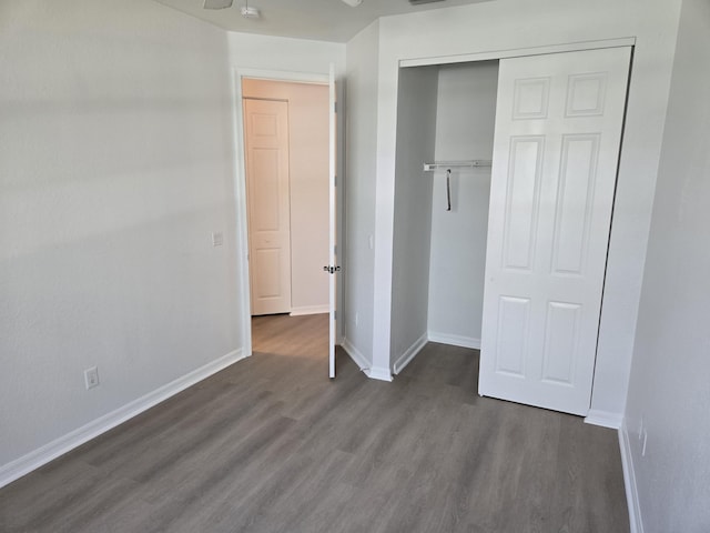 unfurnished bedroom featuring a closet, dark wood-style flooring, and baseboards