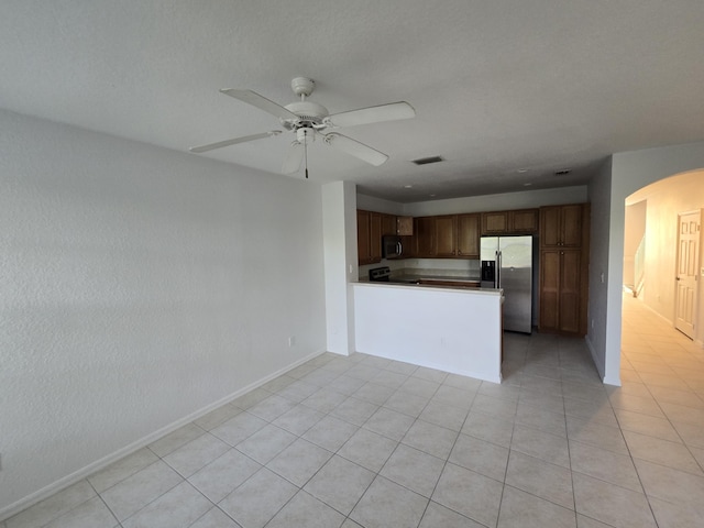 kitchen with visible vents, brown cabinetry, arched walkways, a peninsula, and stainless steel appliances